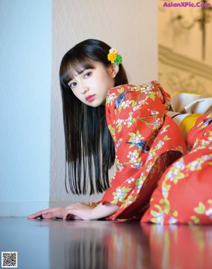 A woman in a red kimono sitting on the floor.