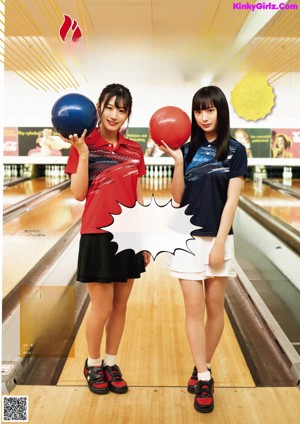 A woman in a blue shirt and white skirt holding a bunch of bowling balls.