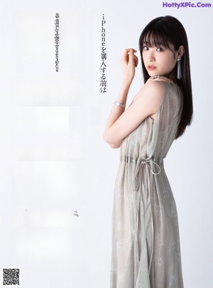A woman with long brown hair wearing a gray dress.