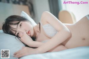 A woman in a white lingerie sitting on a bed.