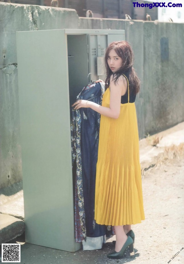 A woman in a yellow dress standing next to a locker.