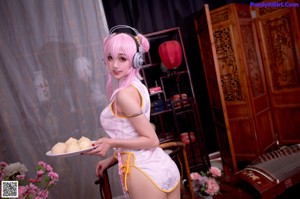 A woman in a pink and white outfit holding a plate of food.