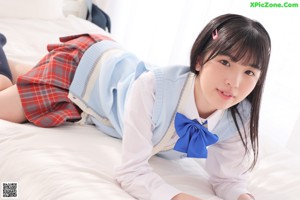 A young woman in a school uniform holding a blue bag.