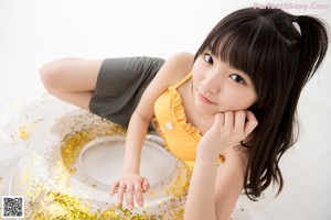 A woman in a yellow top and green skirt posing for a picture.