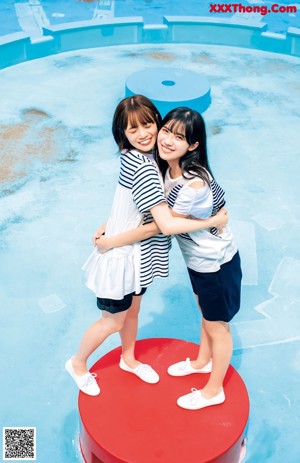 A couple of women sitting next to each other on a blue bench.