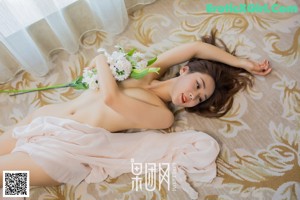 A woman laying on a bed with a bouquet of flowers.