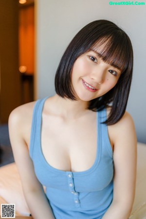 A woman in a blue tank top is putting on her underwear.
