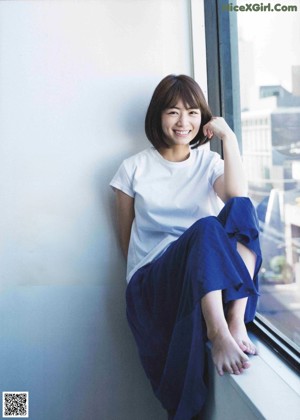 A woman in a white shirt leaning against a window.