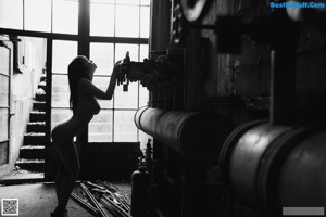 A woman in a gold bikini posing in a factory.