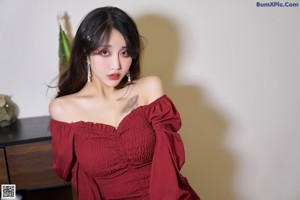 A woman in a red dress sitting on a black couch.