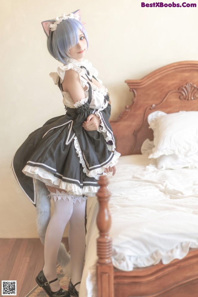 A woman in a maid outfit standing on a bed.