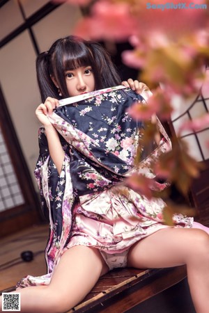 A woman in a kimono sitting on a tatami mat.