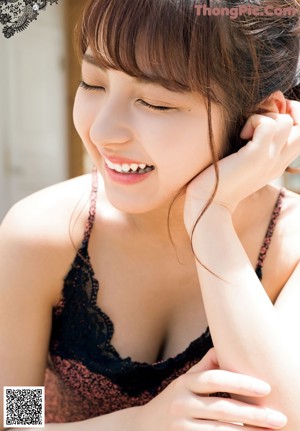 A woman in a pink bra and panties leaning against a wall.