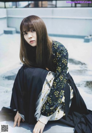 A woman with long brown hair wearing a black dress.