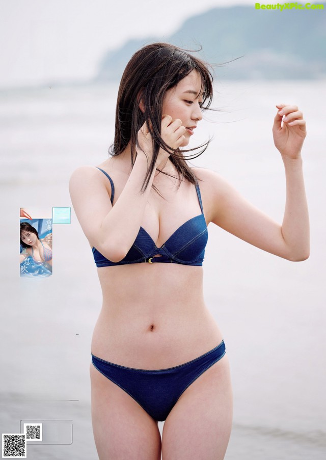 A woman in a blue bikini standing on a beach.