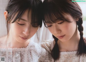 A couple of women sitting on top of a bed.