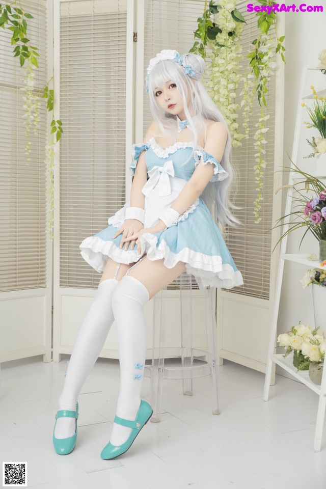 A woman in a blue and white dress sitting on a stool.