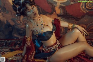A woman in a belly dance costume sitting on a rug.