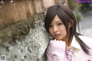 A young woman in a school uniform sitting on the floor.