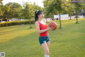 A woman holding a basketball on top of a basketball court.