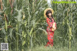 A naked asian woman holding a squash in a field.