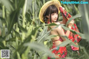 A woman in a straw hat standing in a field of corn.