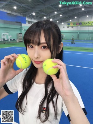 Two young women standing on a tennis court holding tennis rackets.