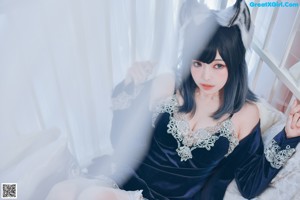 A woman sitting on a couch wearing a cat ears headband.