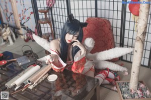 A woman in a red and white outfit sitting on the floor.