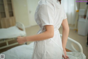 A woman in a white dress sitting on a bed.