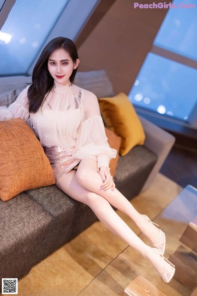 a woman sitting on top of a couch next to a window