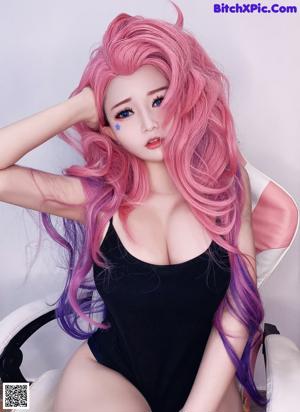 A woman with long pink hair wearing a black dress.