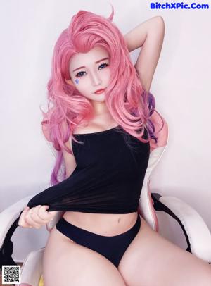 A woman with long pink hair wearing a black bra top.