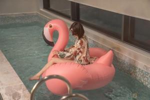 A woman in a white bathing suit is floating on an inflatable flamingo.