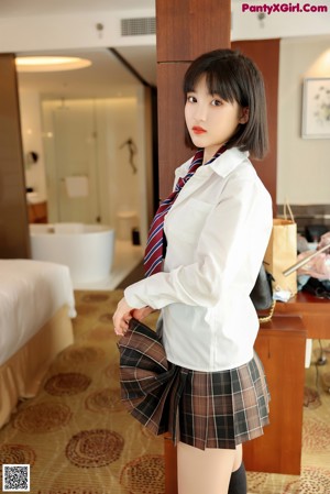 A woman in a white shirt and black stockings standing in front of a window.
