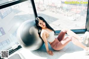 A woman in a gray top and gray pants posing in a gym.