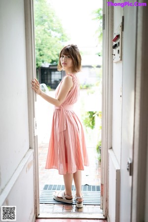 A woman in a pink dress holding an umbrella.