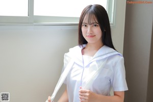 A young woman in a school uniform sitting on the floor.