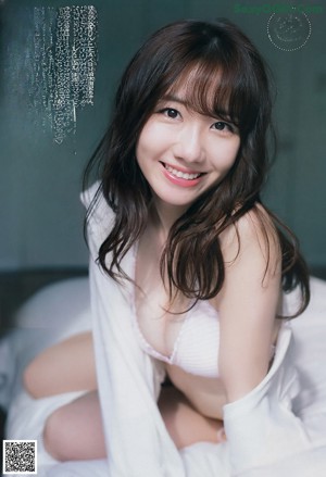 A woman in a white hoodie leaning against a wall.