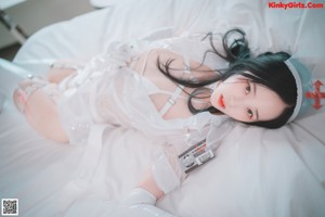 A woman in a white nurse outfit sitting on a white couch.