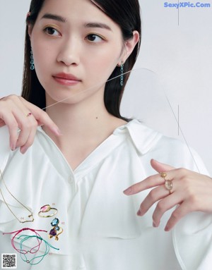 A woman wearing a gray sweater and a necklace.