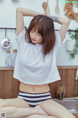 A woman sitting on a kitchen counter holding a bowl of food.